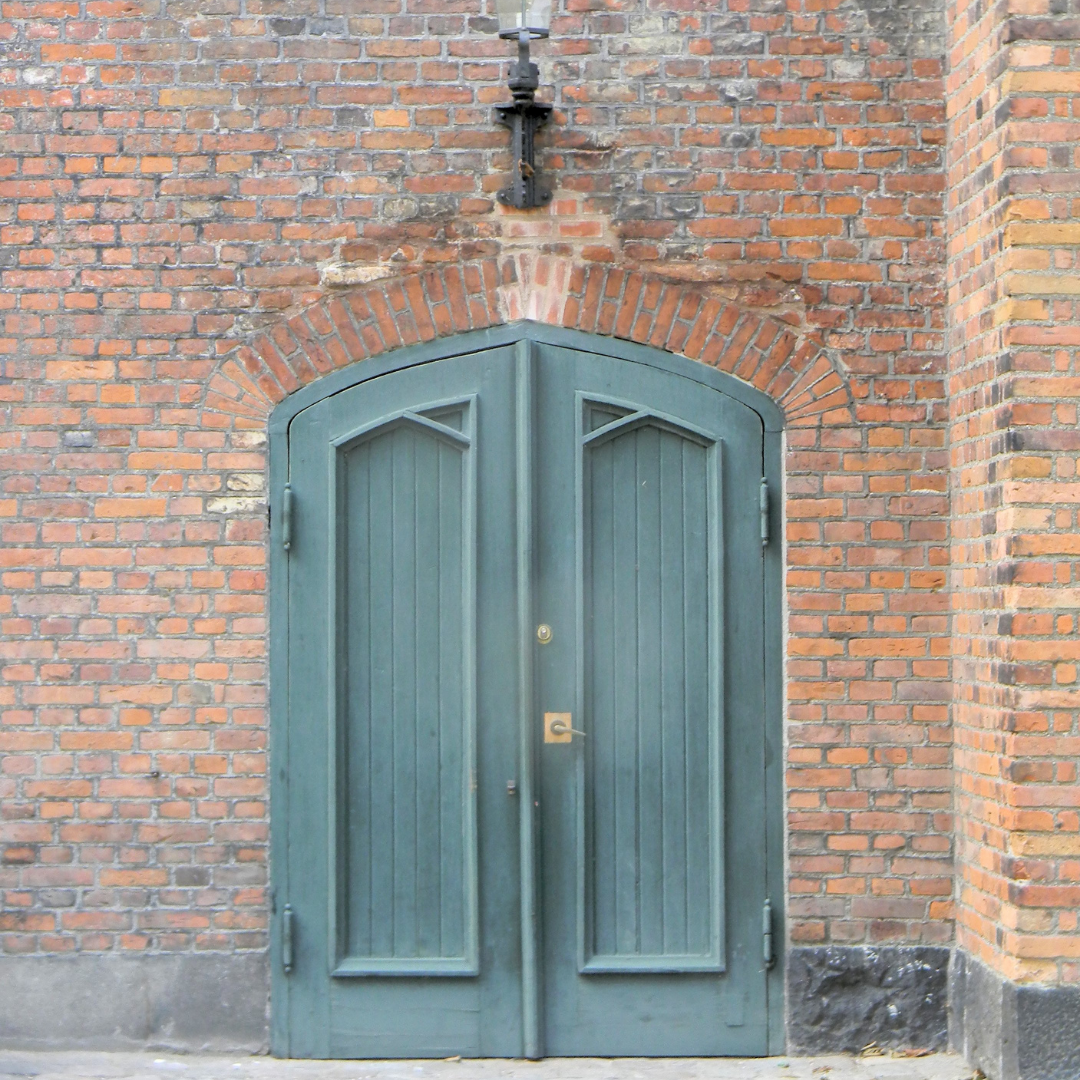 red brick wall with a neat antique teal door