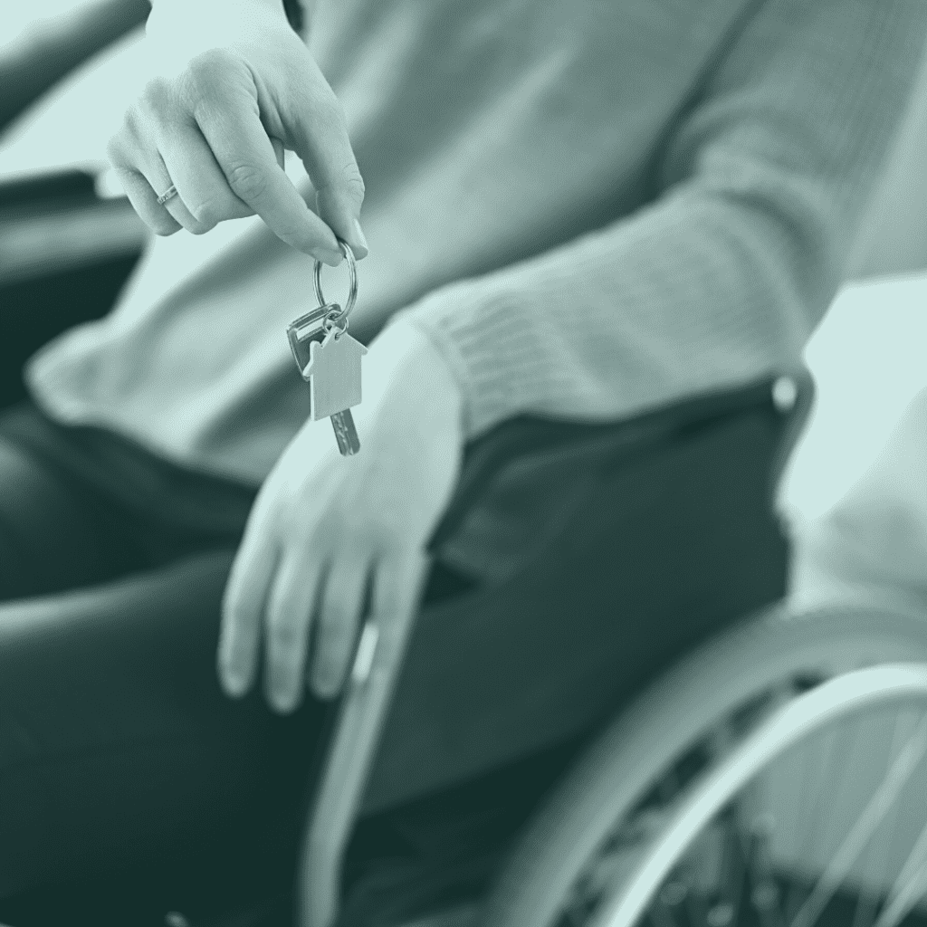 Woman in a wheelchair holding a keychain with one key and a little house keychain on it